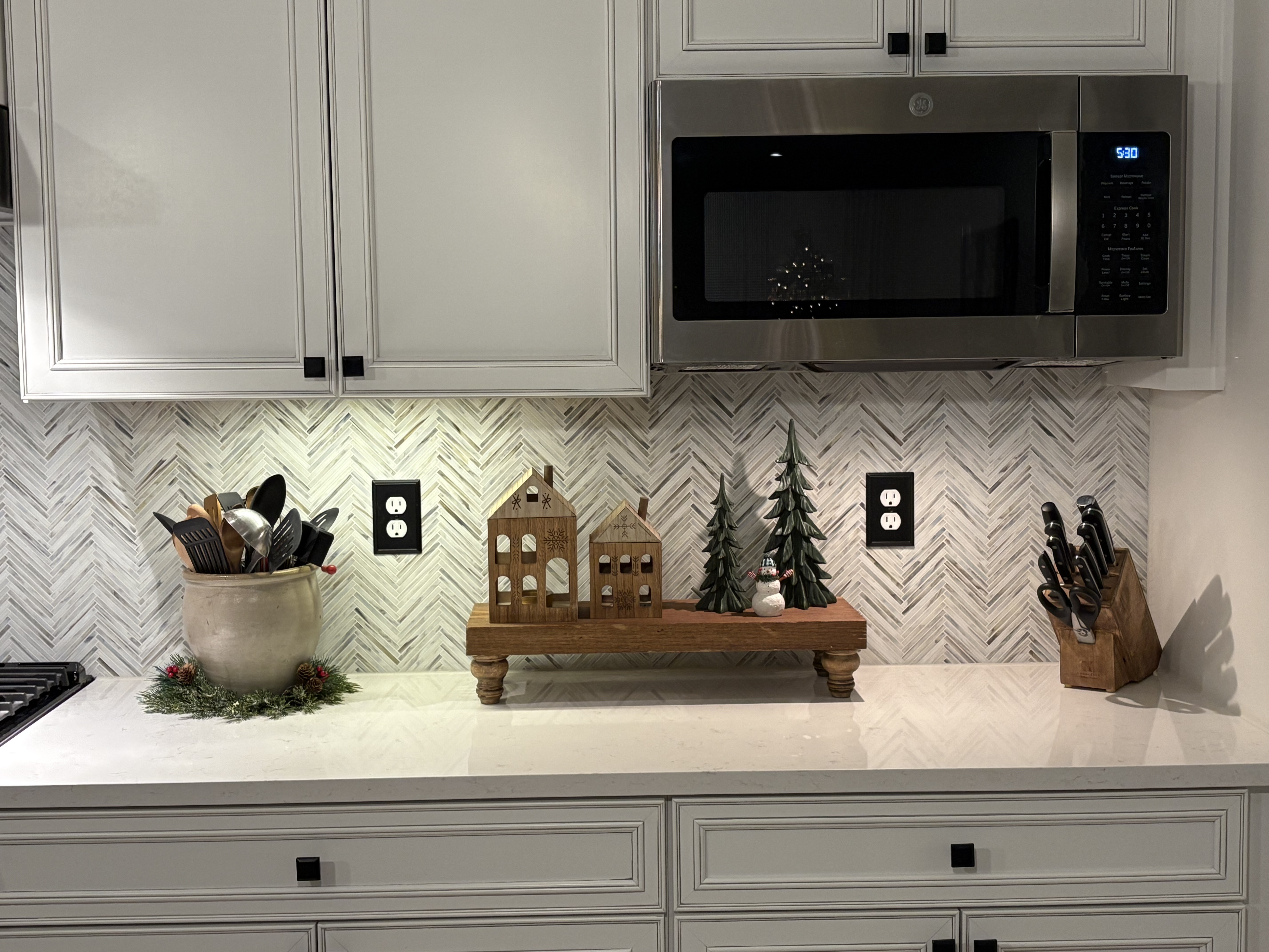 The right view of a kitchen with a white tile backsplash showing the overhead microwave